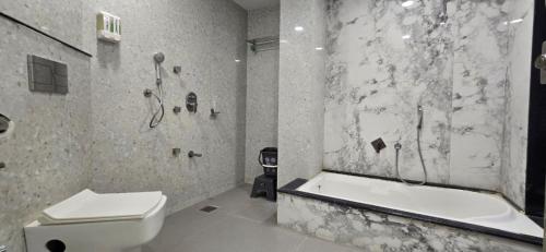 a bathroom with a toilet and a tub and a sink at Hotel Asopalav in Junagadh
