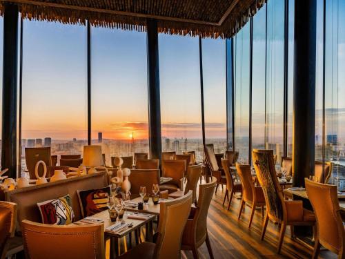 a restaurant with tables and chairs in a room with windows at Too Hotel & Spa Paris - MGallery Collection in Paris