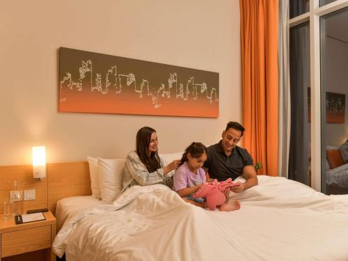 a family is sitting on a bed at Adagio Doha in Doha