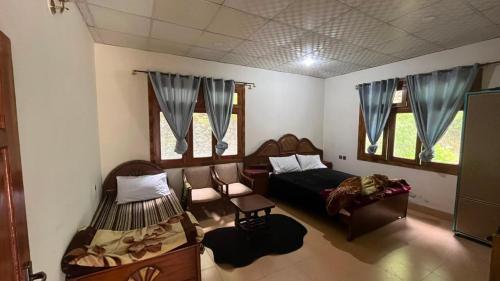 a bedroom with a bed and a couch and windows at Escape cottage Nathia Gali 