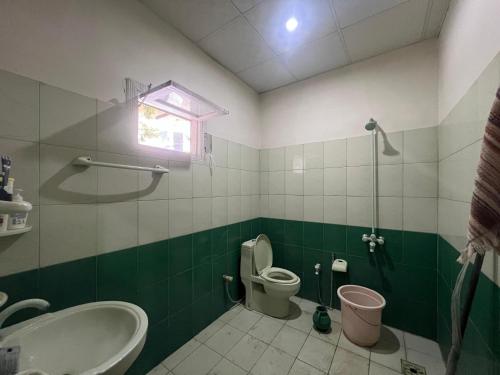 a green and white bathroom with a toilet and a sink at Escape cottage Nathia Gali 