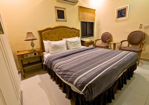 a bedroom with a bed with two chairs and a television at Hotel New Panorama in Lahore