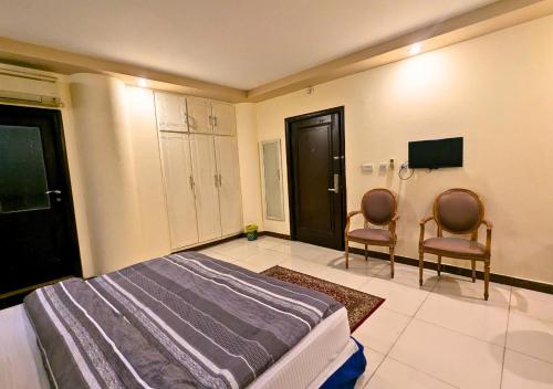 a bedroom with two chairs and a bed and a tv at Hotel New Panorama in Lahore