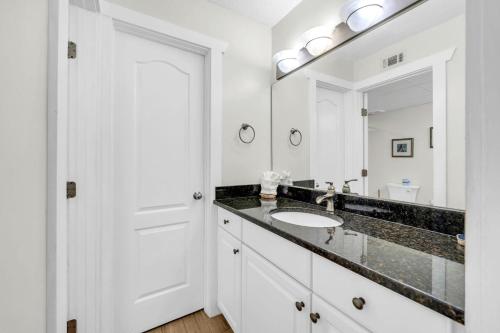 a white bathroom with a sink and a mirror at Aquavista 304W in Panama City Beach