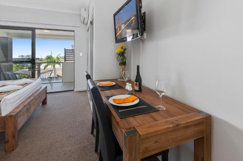 a dining room with a wooden table with food and wine glasses at La Vida on Anzac in Redcliffe