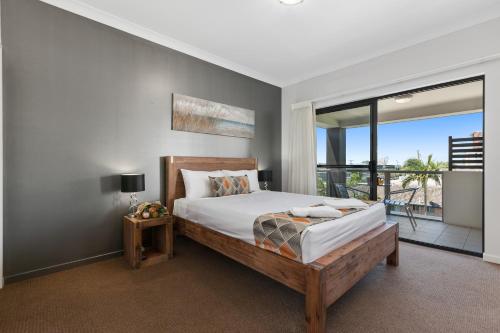 a bedroom with a large bed and a balcony at La Vida on Anzac in Redcliffe