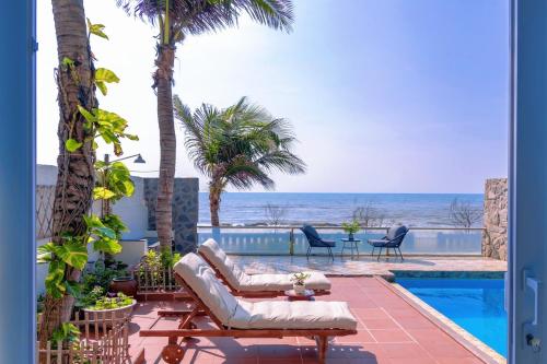 a patio with a pool and palm trees and the ocean at Private Ocean-View Pool Villa, Phan Thiet Beach in Tiến Thành