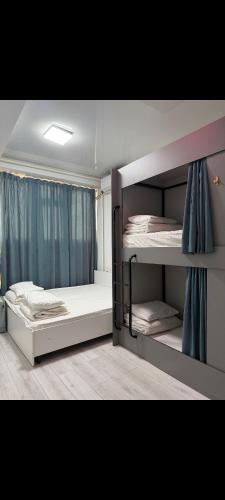 a bedroom with two bunk beds with blue curtains at Deutsch Hostel Osh in Osh