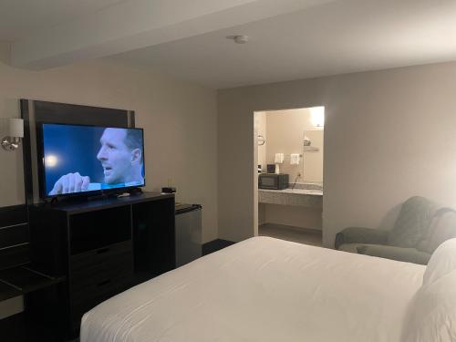a hotel room with a bed and a flat screen tv at Landmark Inn in Osawatomie