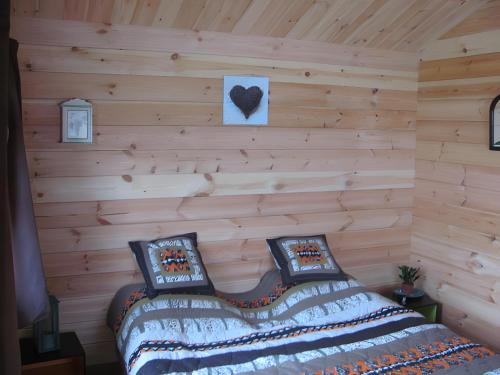 a bedroom with wooden walls and a bed with pillows at Du puits de Riquier écologique in Régusse