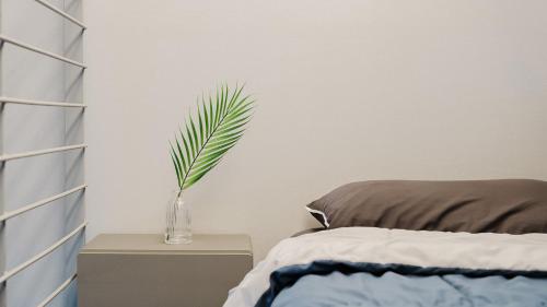 a plant in a vase on a night stand next to a bed at Sokcho Night Sky Pension in Sokcho