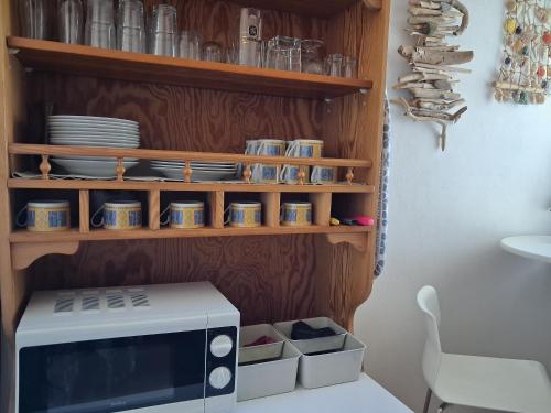a kitchen with a microwave and shelves with dishes at Satori in Władysławowo