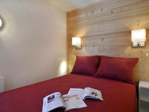 a bedroom with a red bed with two newspapers on it at Appartement 2 pièces rénové 5 pers. au cœur des pistes - FR-1-181-952 in Plagne Bellecote