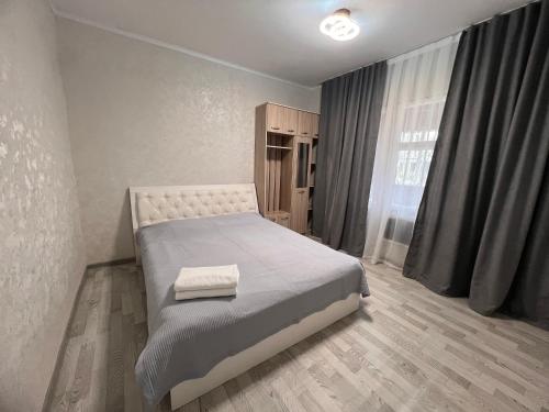 a bedroom with a bed and a large window at Altyn Sandyk in Karakol