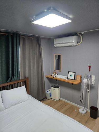 a bedroom with a bed and a desk with a fan at Art and Stay in Suncheon