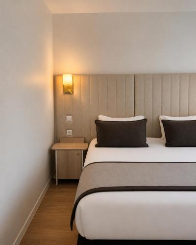a hotel room with a large bed and a lamp at Hôtel Derby Eiffel in Paris