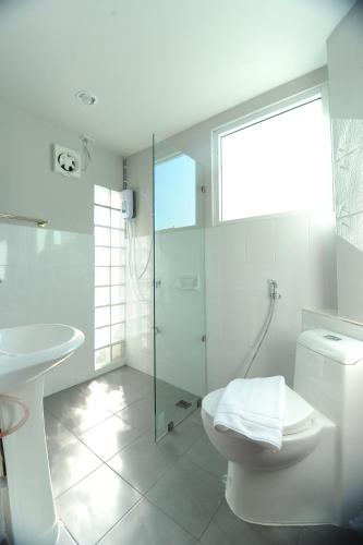 a white bathroom with a toilet and a sink at Nanya Hotel Chiang Mai in Chiang Mai