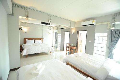 a bedroom with two beds with white sheets at Nanya Hotel Chiang Mai in Chiang Mai