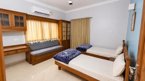 a bedroom with two beds and a bench at Sky Villa in Trichūr