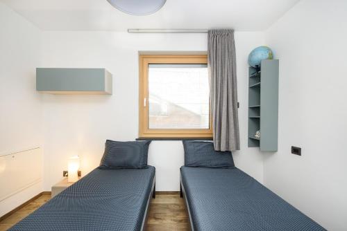 two beds in a room with a window at Alpine Aura Loft- Privacy, Relax, Mountain View in Saint-Christophe