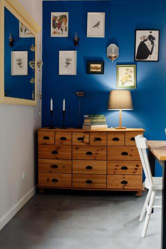 a bedroom with a blue wall and a dresser with a lamp at Leśniczówka Dobrocin in Małdyty