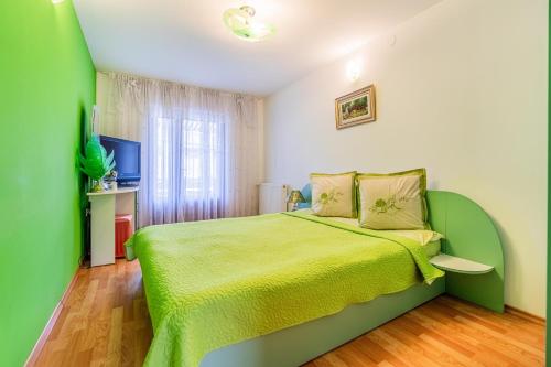 a green bedroom with a bed and a television at Casa Buga in Telega