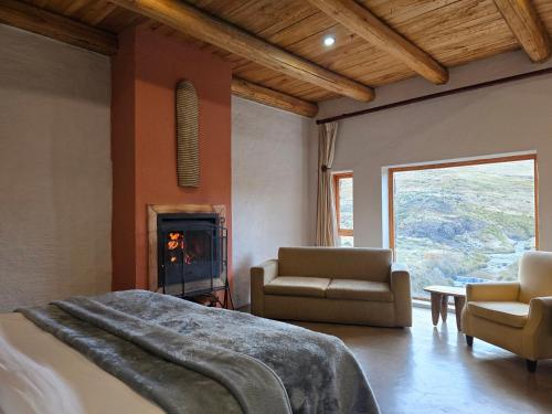 a bedroom with a bed and two chairs and a fireplace at Tenahead Lodge & Spa in Rhodes