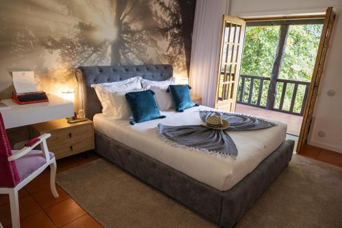 a bedroom with a bed with blue pillows and a window at Quinta Linhas da Primavera in Guimarães
