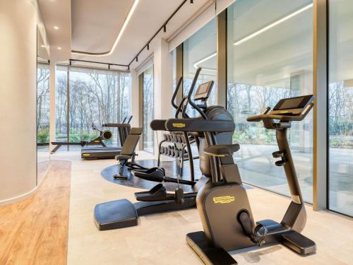 a gym with several treadmills and elliptical machines at Mövenpick Hotel Brussels Airport in Zaventem