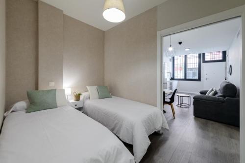 a bedroom with two beds and a living room at Torrejón Suites 2 in Torrejón de Ardoz