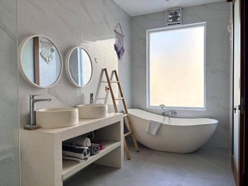 a bathroom with two sinks and a tub and mirrors at Amy Guesthouse Nusa Dua in Nusa Dua