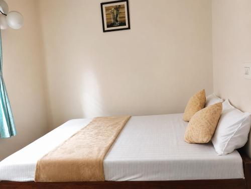 a bedroom with a bed with white sheets and pillows at Neartown Homestay in Kushālnagar