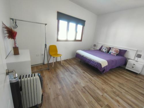 a bedroom with a bed and a yellow chair at Apartamento Villa Alpispa in Agüimes
