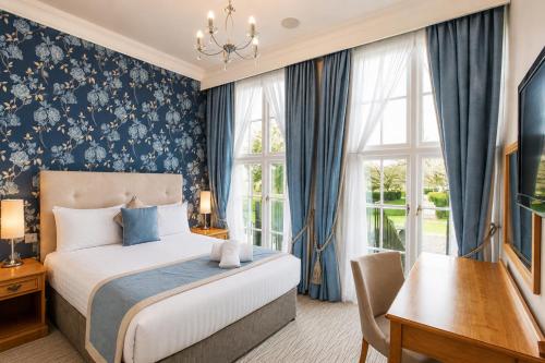 a bedroom with a bed and a desk and window at Hazlewood Castle & Spa in Tadcaster