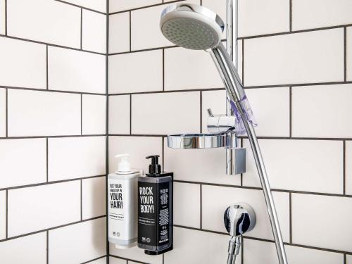 a shower head and a blow dryer on a bathroom wall at ibis Poitiers Site du Futuroscope in Chasseneuil-du-Poitou