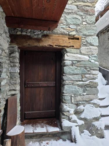 a wooden door in a stone building in the snow at la casa del marmottaio in Crépin
