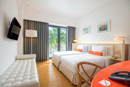 a hotel room with two beds and a desk at HARRIS Hotel & Conventions Malang in Malang