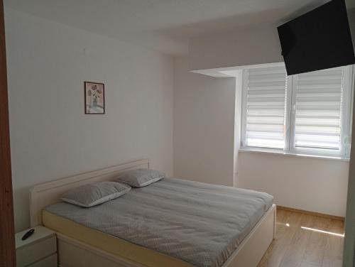 a white bedroom with a bed and a window at Vitez apartman in Vitez