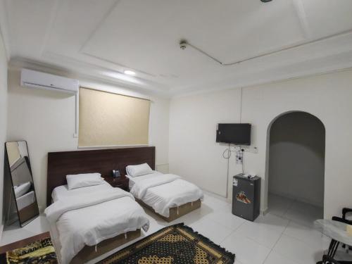 a bedroom with two beds and a flat screen tv at فندق فاديه الذهبي in ‘Ushayrah