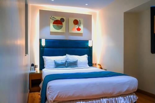 a bed with a blue headboard in a room at Middleton Inn in Kolkata