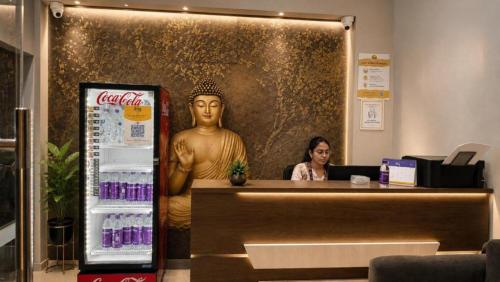 a woman sitting at a cash register in a store with a statue at Hotel Rise Grand Kukatpally Near Hitex Exhibition Center & Nexus Mall, Yashoda Hospital in Hyderabad