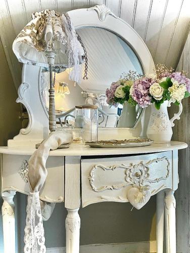 a dressing table with a mirror and flowers on it at La Porte Bleue le grenier des Anges in Saint-Pierre