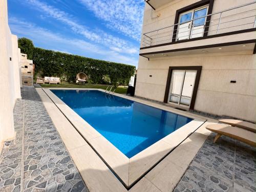 a swimming pool in front of a house at La Dolce Villa with Private Pool in Borg El Arab