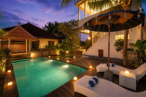a pool with chairs and an umbrella next to a house at Liam Private Villa in Ubud