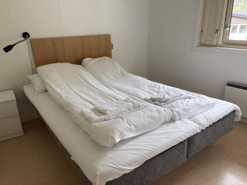 an unmade bed with white sheets on top of it at Standard Rom in Fjæra