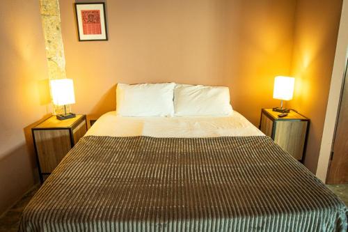 a bed in a room with two lamps on tables at Capital O Adhoc Barrio Antiguo in Monterrey
