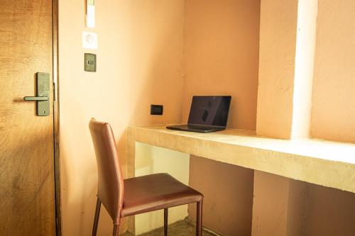 a chair sitting next to a desk with a laptop computer at Capital O Adhoc Barrio Antiguo in Monterrey