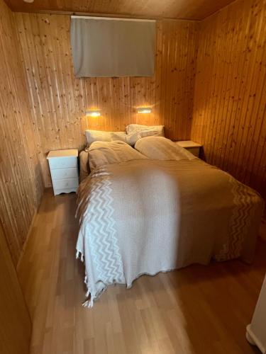 a bedroom with a bed with wooden walls and wood floors at Senja seaside retreat in Senja