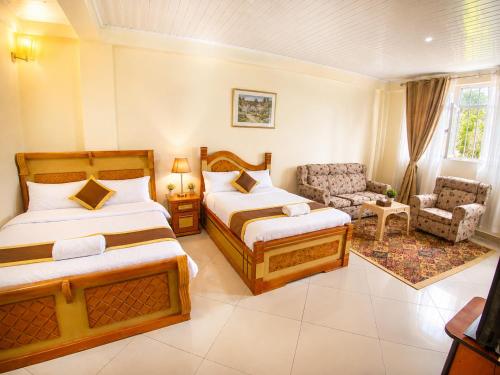 a hotel room with two beds and a chair at Avi Guest House in Addis Ababa