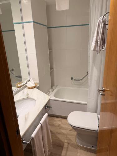 a bathroom with a tub and a toilet and a sink at Hotel Canelas in Portonovo